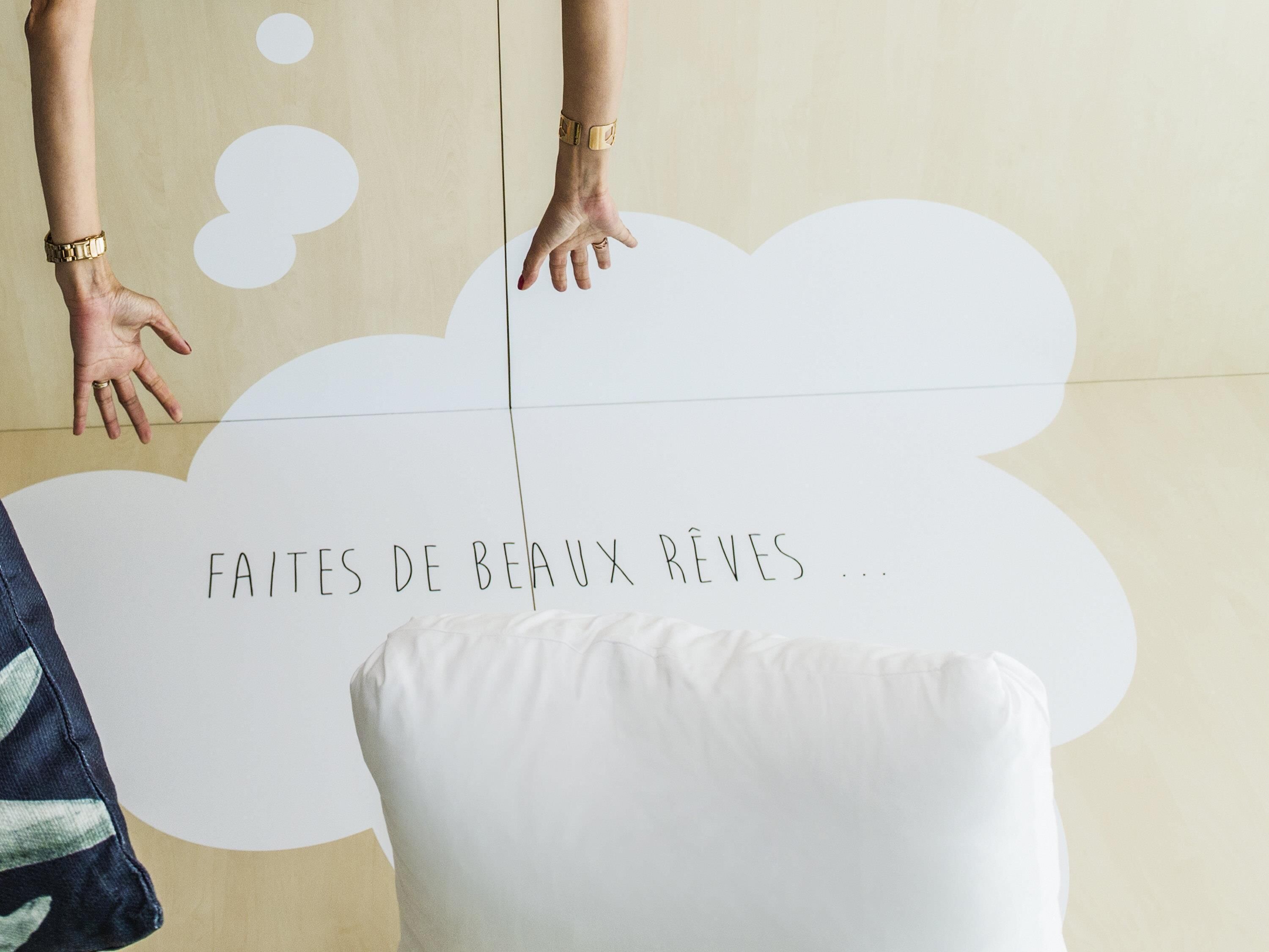 A room with a white pillow and a wall with a text that reads 'FAITES DE BEAUX RÈVES ...'.