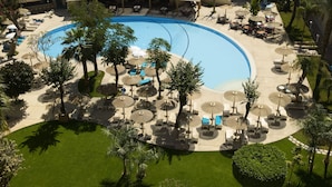 Vue aérienne d’un complexe hôtelier doté d’une grande piscine, de chaises longues et de parasols.