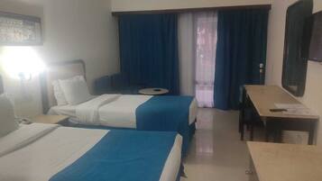 Habitación de hotel con dos camas, un escritorio, una silla y una ventana con cortinas.