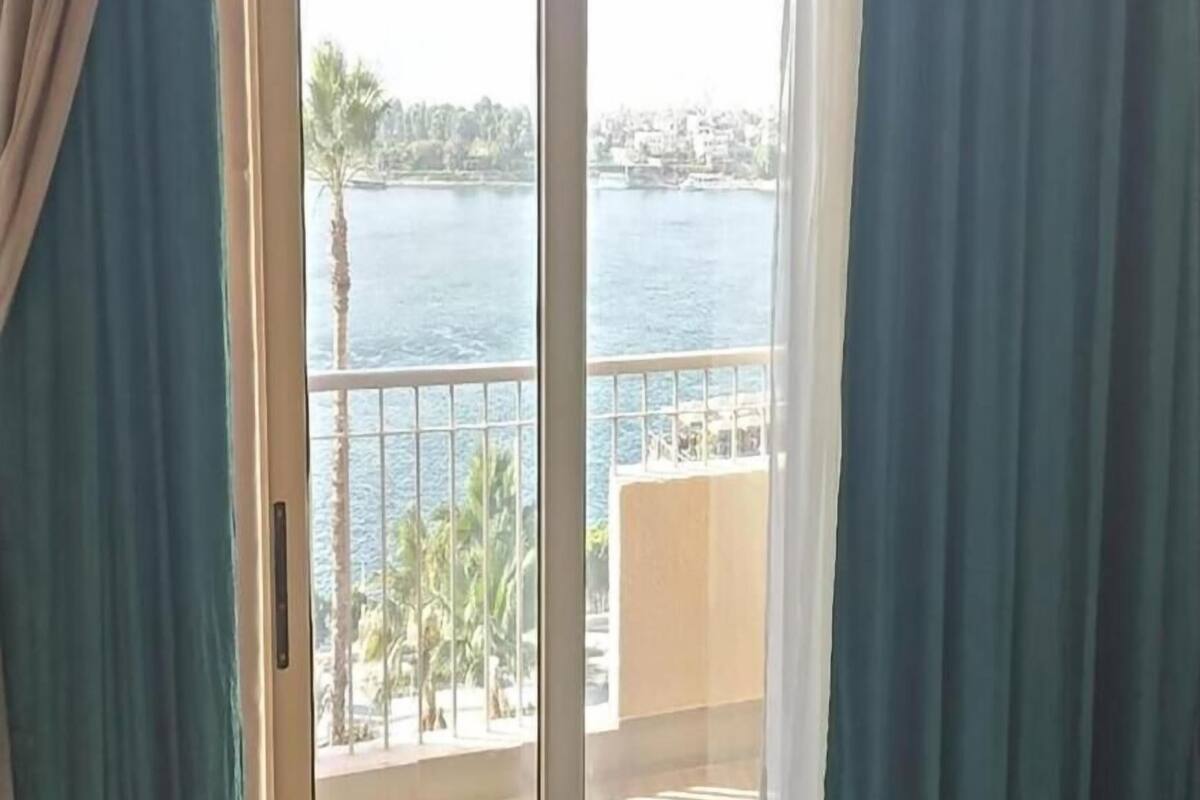 A view from a balcony with a railing, overlooking a body of water and a distant shoreline.