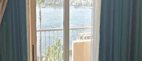 A view from a balcony with a railing, overlooking a body of water and a distant shoreline.