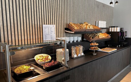A buffet setup with various food items and a coffee machine.