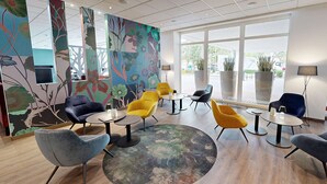 A modern lounge area with a variety of seating options, including armchairs and sofas, arranged around small tables.