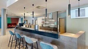 A modern bar area with a counter, bar stools, and hanging pendant lights.