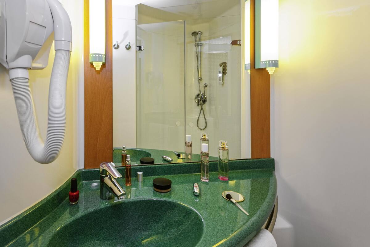 Ein Badezimmer mit einem grünen Waschbecken, einem Föhn und einer Dusche.