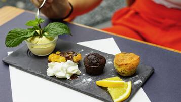 Um prato de sobremesa com sorvete, chantilly, um muffin de chocolate e fatias de limão.