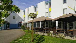 Um hotel moderno com área externa para sentar e um gramado bem cuidado.