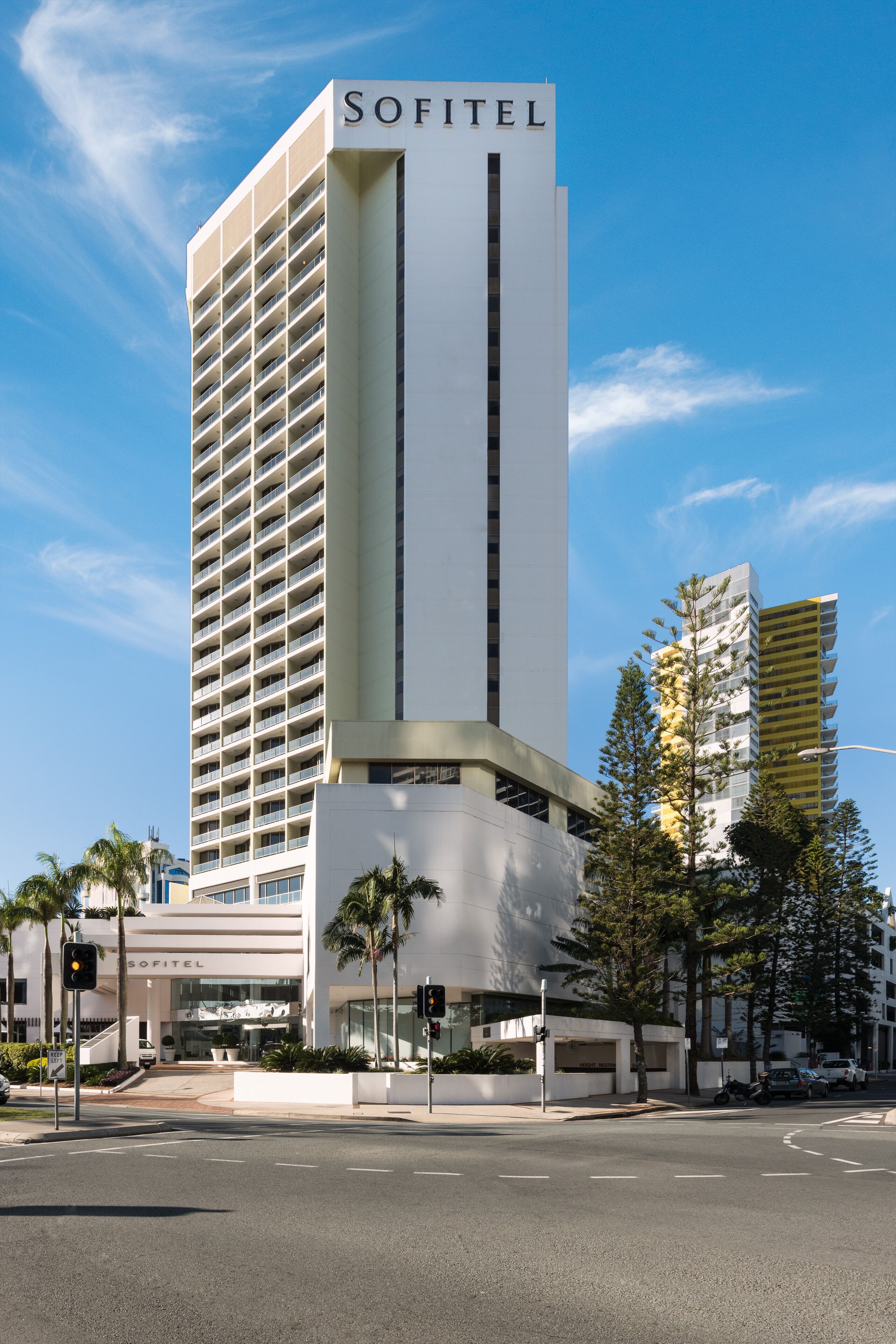 A tall, modern hotel with a prominent 'SOFITEL' sign, featuring a clean, white facade and a vertical stripe design.