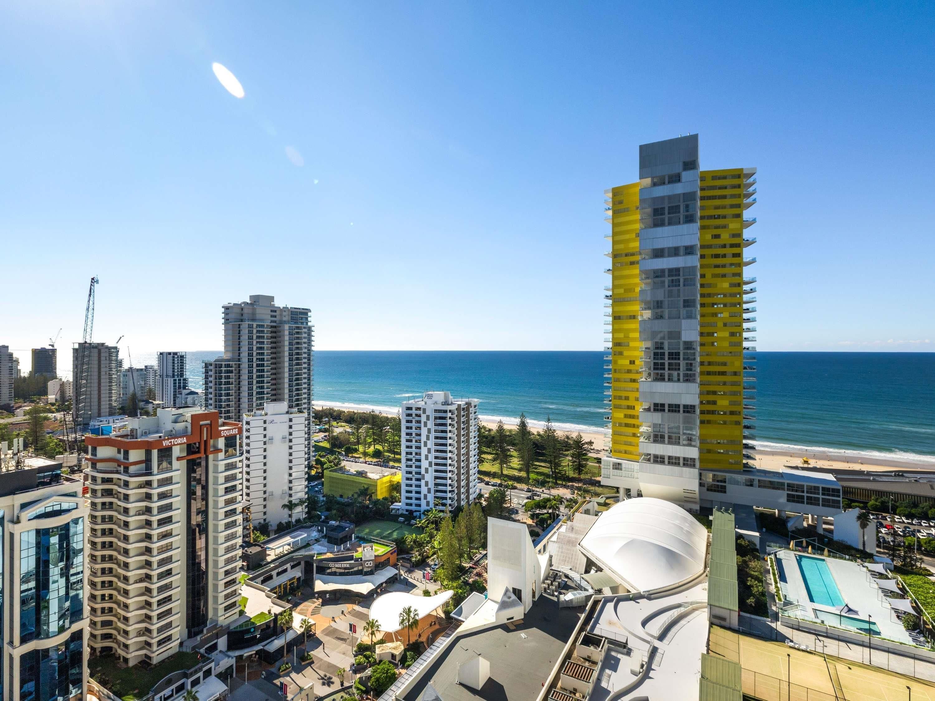 A coastal cityscape with high-rise buildings, a beach, and a large white dome structure.
