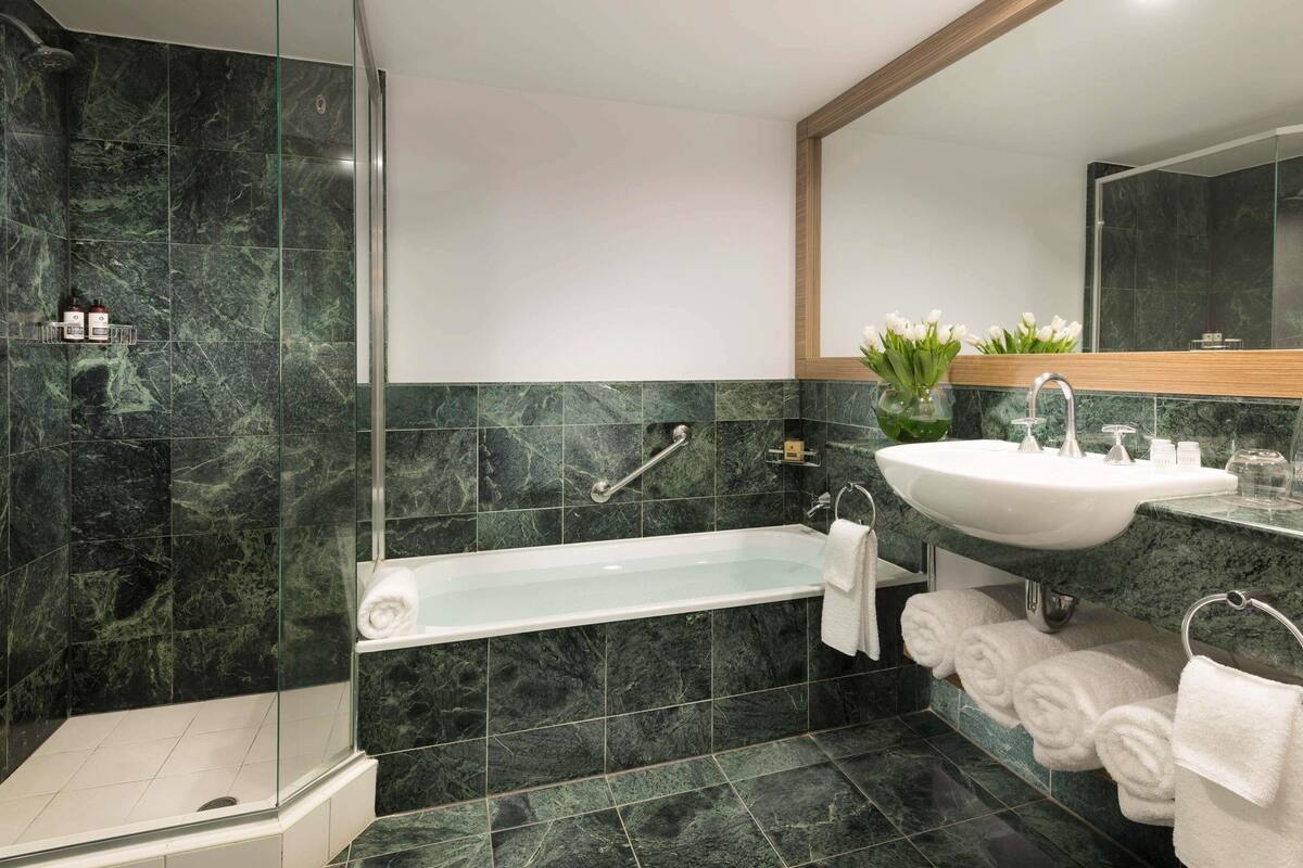Une salle de bain moderne dotée d’une douche à parois de verre, d’une baignoire sur pieds et d’un meuble-lavabo avec un évier et un miroir.