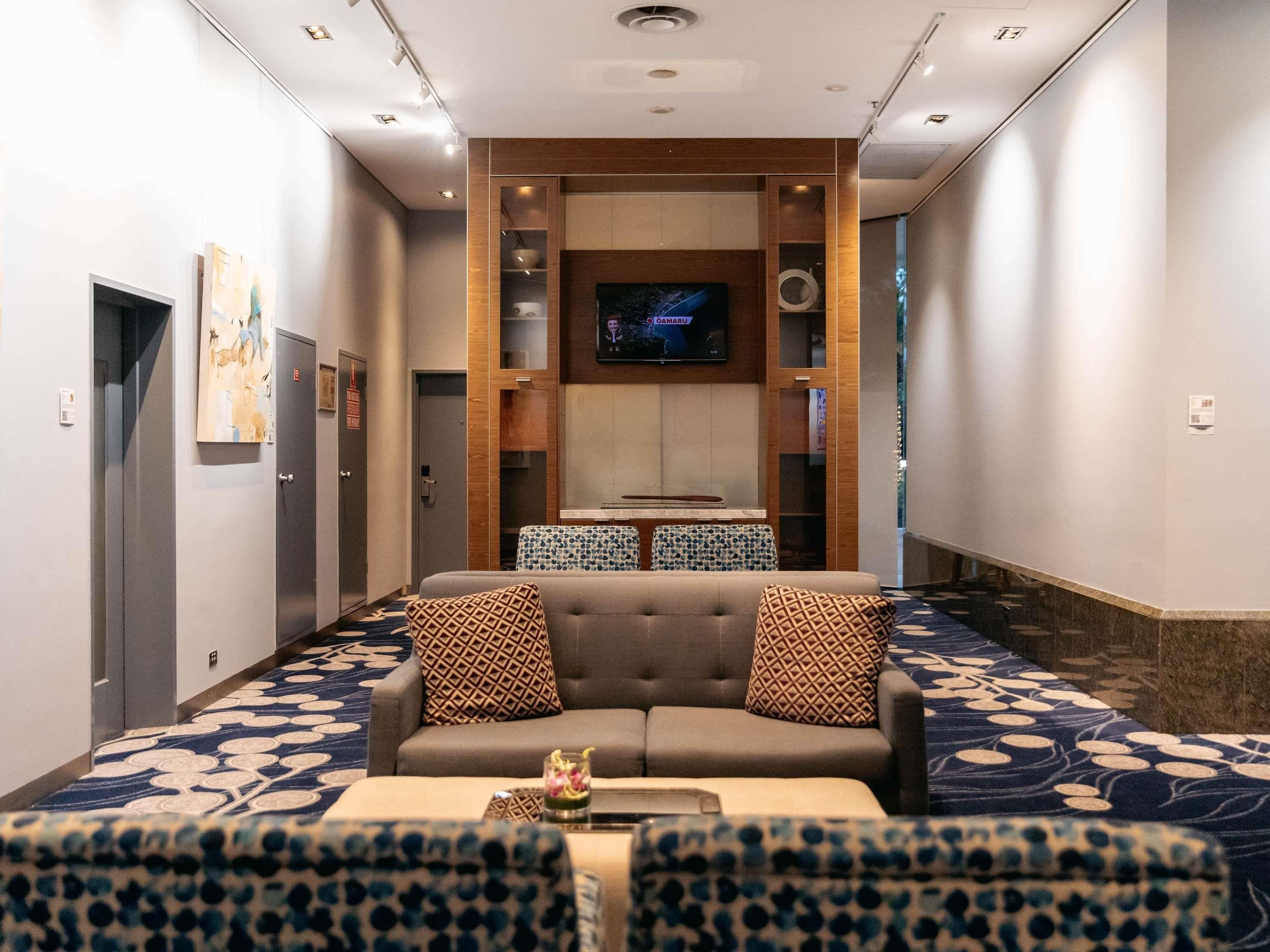 A hotel lobby with a sofa set, a television, and a patterned carpet.