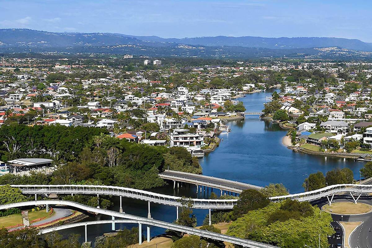 Une rivière traversée de ponts, une ville avec des maisons et, au loin, une chaîne de montagnes.