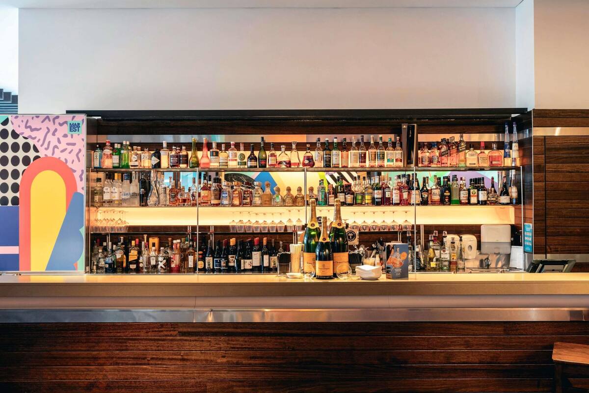 Un espace bar doté de plusieurs étagères remplies de bouteilles d’alcool et de verres.