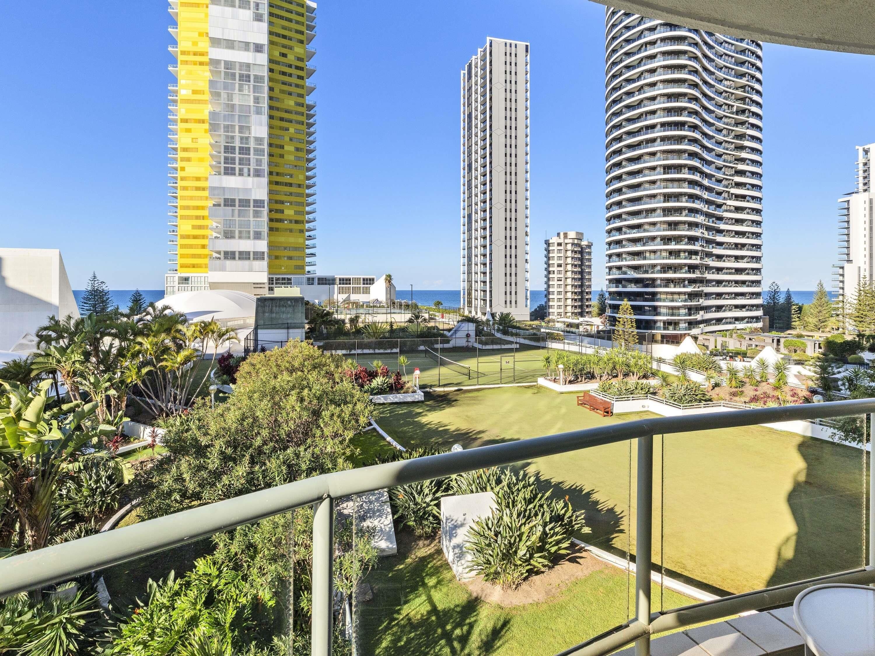 A residential area with high-rise buildings, a well-maintained lawn, and a clear view of the ocean.