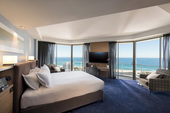 A hotel room with a large bed, a desk, a TV, and a view of the ocean. - Sofitel Gold Coast Broadbeach (Broadbeach)