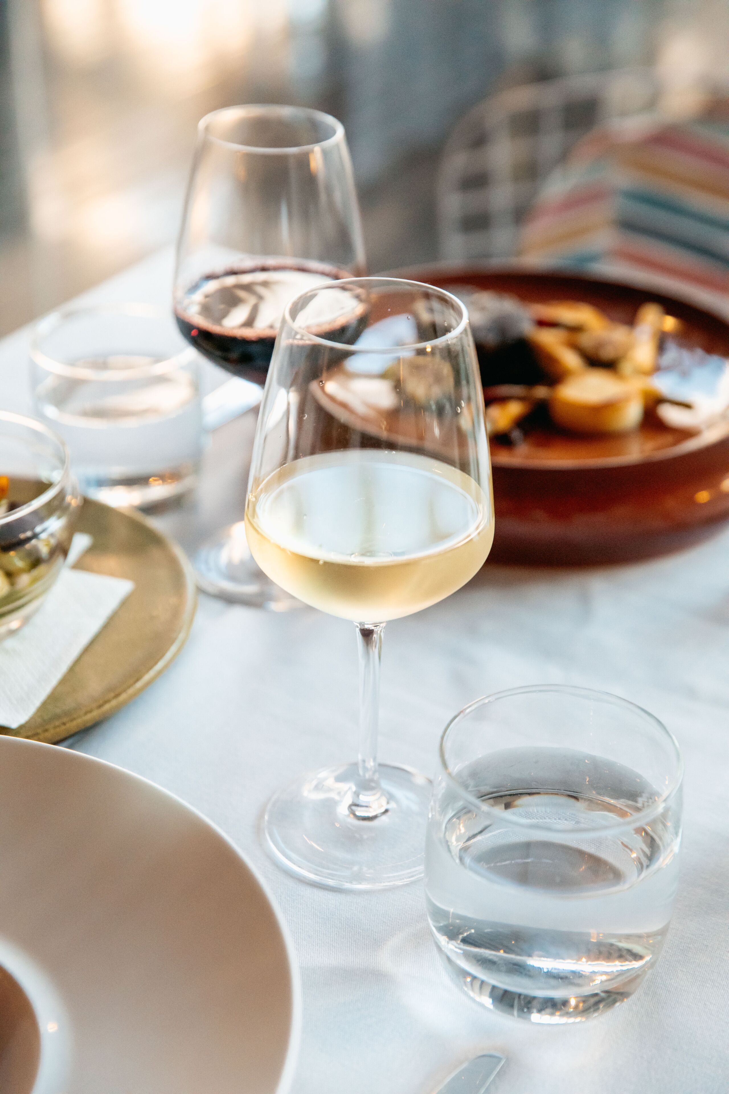 Une table à manger avec des verres à vin, un verre à eau et une assiette de nourriture.