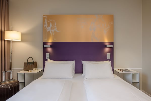 A hotel room with a bed, a nightstand, a lamp, a suitcase, and a wall art piece. - Congress Hotel Mercure Nürnberg an der Messe (Nuremberg)