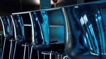 A bar area with modern bar stools and a martini glass on a table.