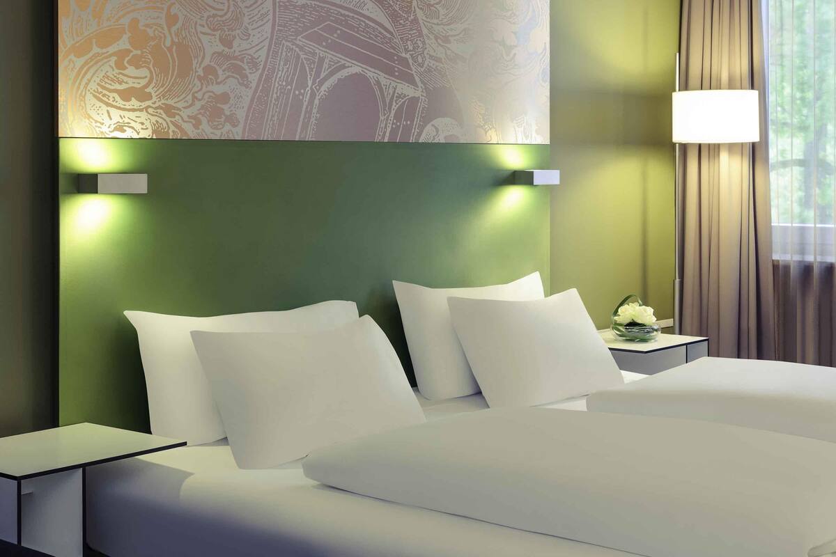 A hotel room with a bed, nightstands, a lamp, and a decorative wall piece.