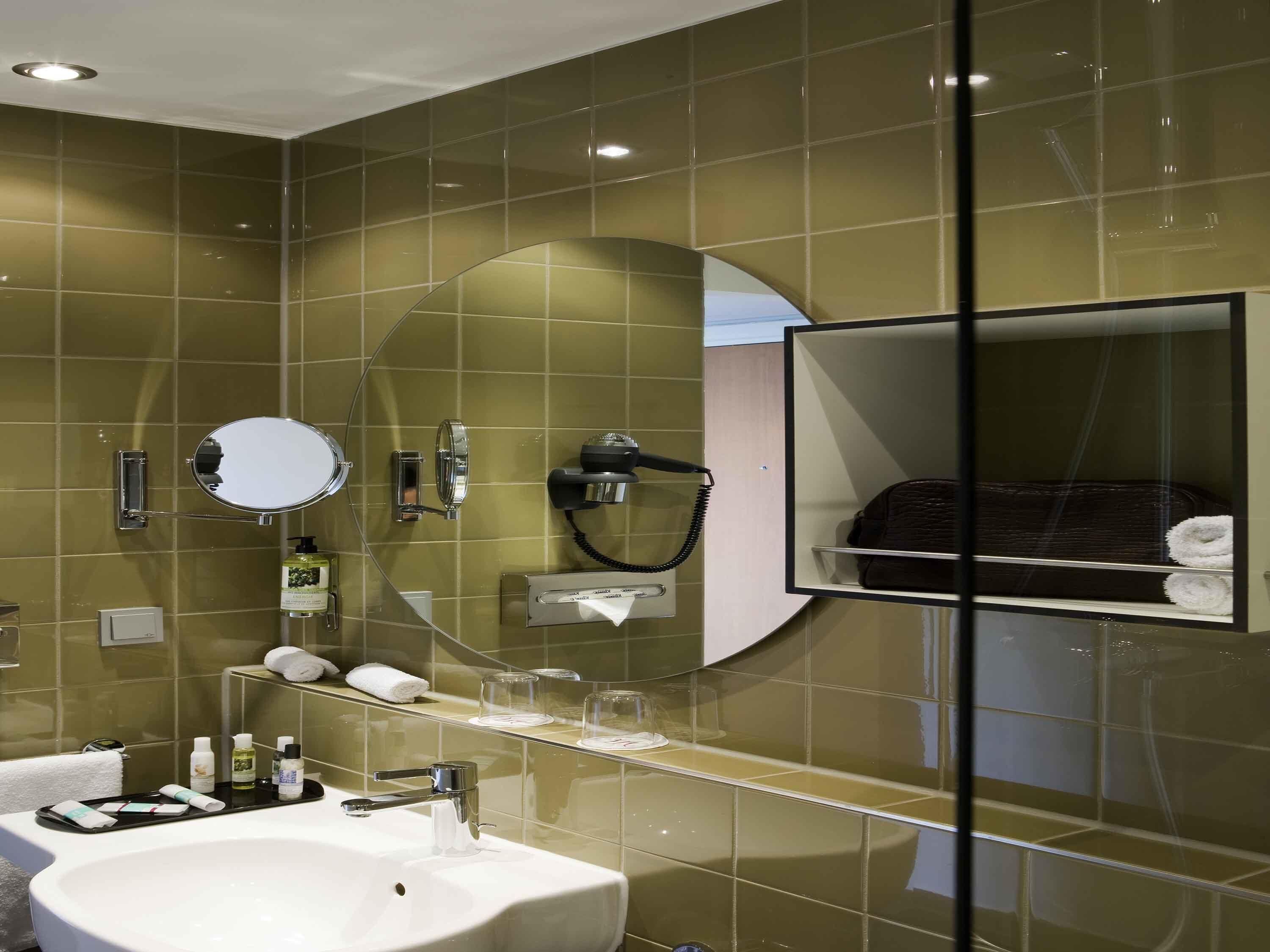 A bathroom with a sink, mirror, towel rack, and a glass shower enclosure.