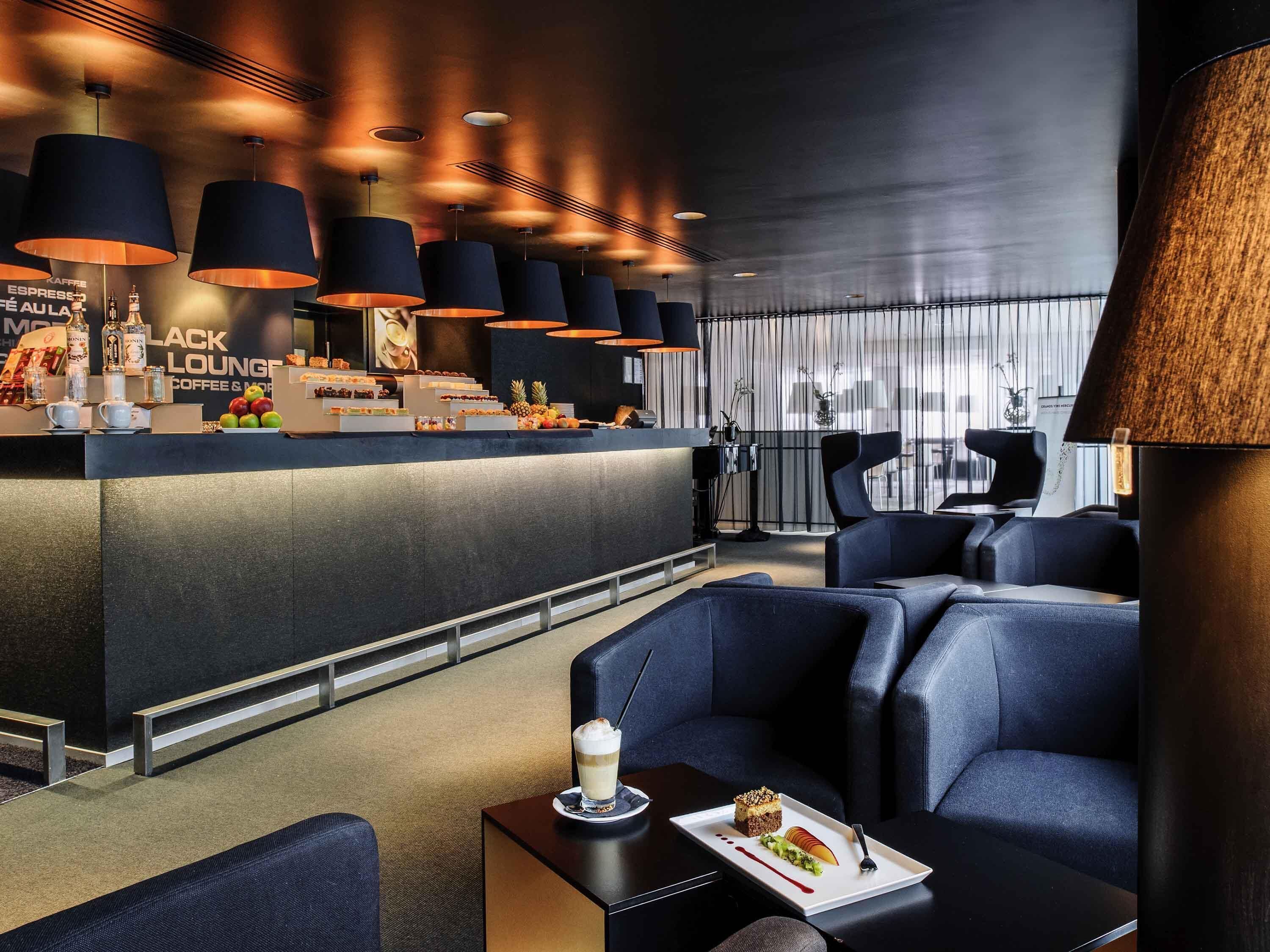 A modern lounge area with a bar, seating, and a view of the city.