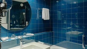 A modern bathroom with a white sink, a round mirror, and a bathtub.