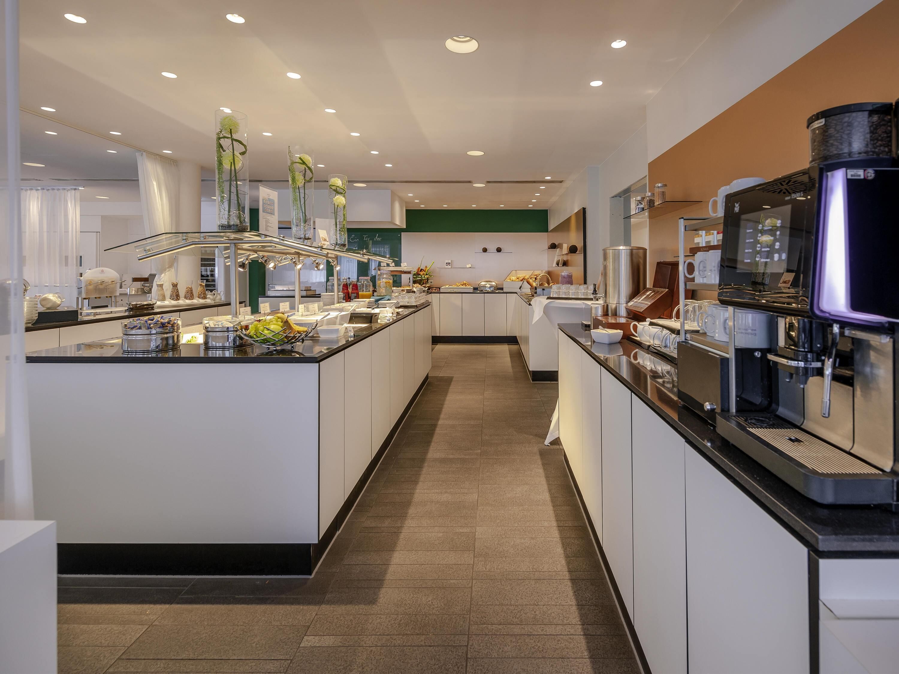 Uma cozinha de hotel moderna, com uma ilha central, equipada com diversos eletrodomésticos e alimentos.
