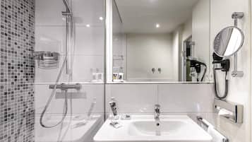 Un baño moderno con ducha, lavabo, espejo y teléfono.