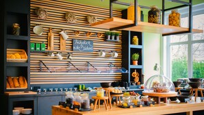 A breakfast bar with wooden shelves, jars, and a chalkboard sign. - Vienna House Easy by Wyndham Bad Oeynhausen (Bad Oeynhausen)