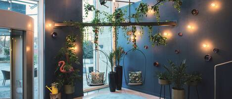 Un interior moderno con un amplio ventanal, una pared azul y diversas plantas.
