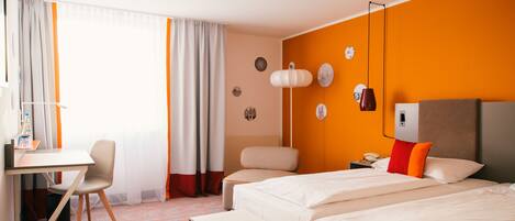 A hotel room with two beds, a desk, a chair, and a small table.