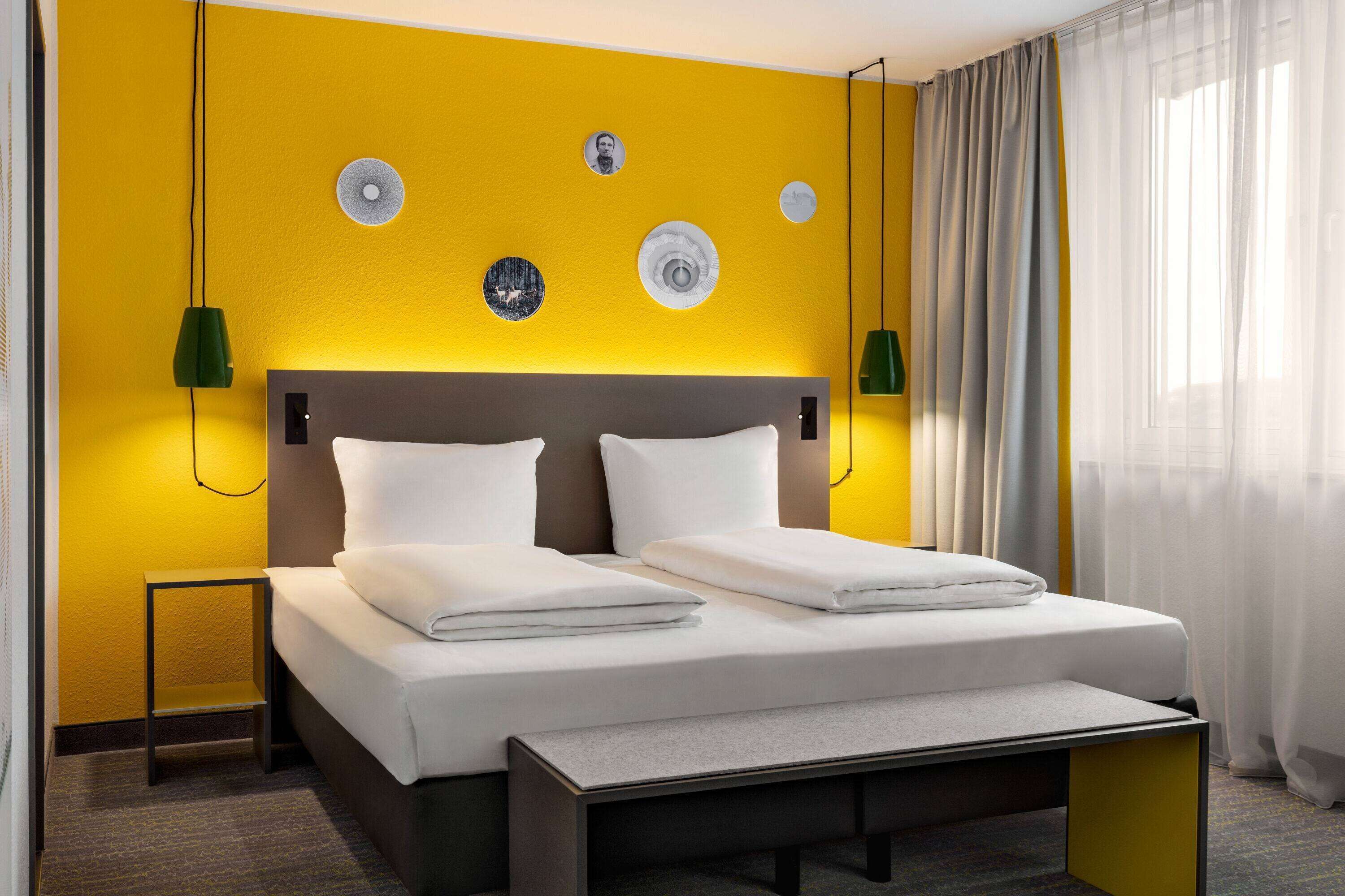 Una habitación de hotel con cama, mesitas de noche y cabecera.
