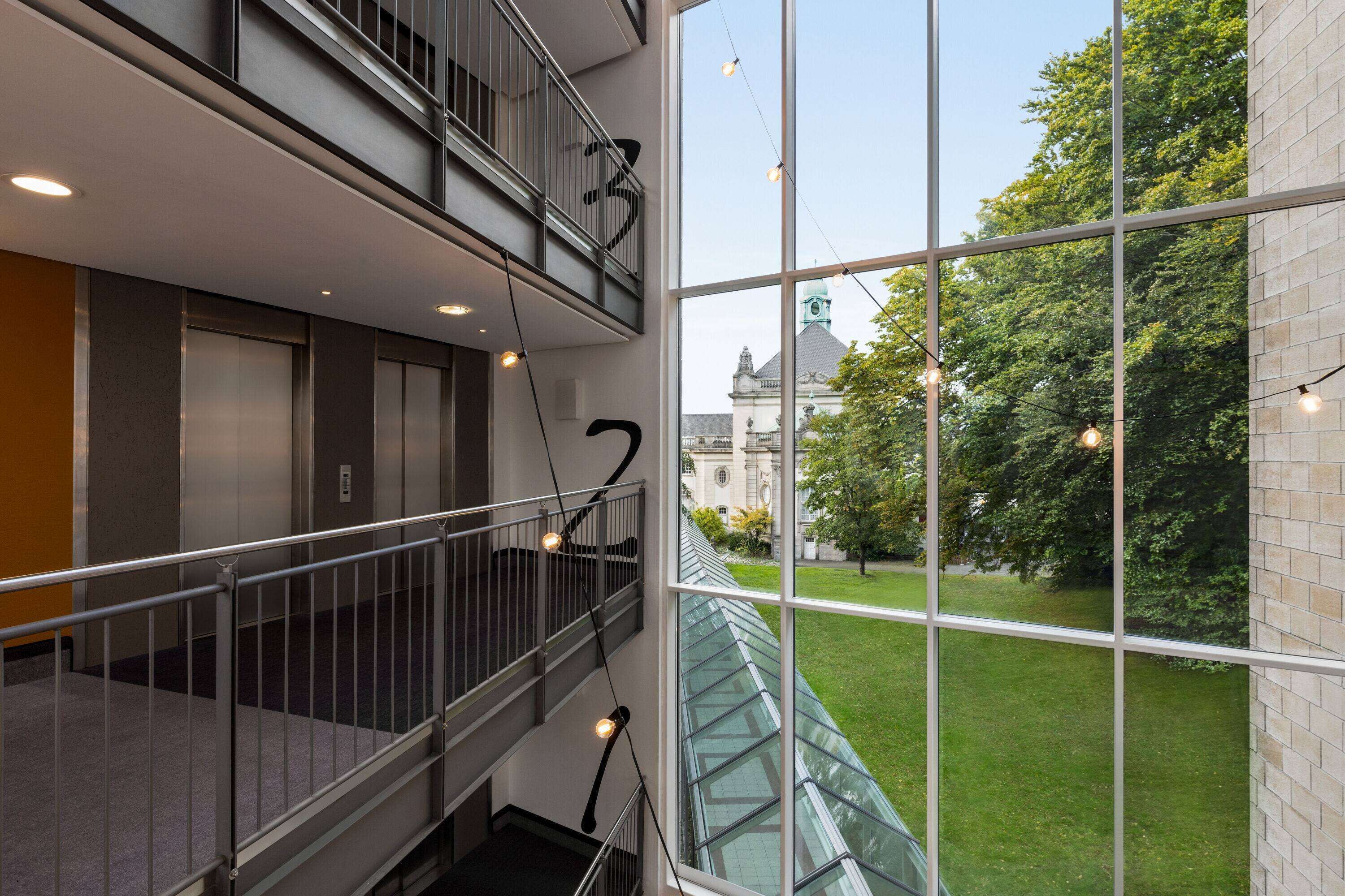 A multi-level interior with a glass railing overlooking a courtyard.