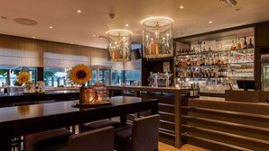 Un espace bar doté d’un long comptoir, de nombreux sièges et d’une vaste sélection de boissons alcoolisées.