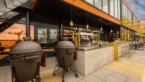 Un espace extérieur aménagé avec un bar, deux grands barbecues et une vue sur le coucher du soleil.