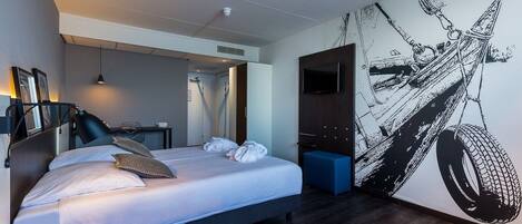 Una habitación de hotel moderna con una cama grande, un escritorio y un mural en la pared.
