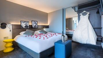 Een moderne hotelkamer met een groot bed, een nachtkastje, een spiegel en een hangende jurk.