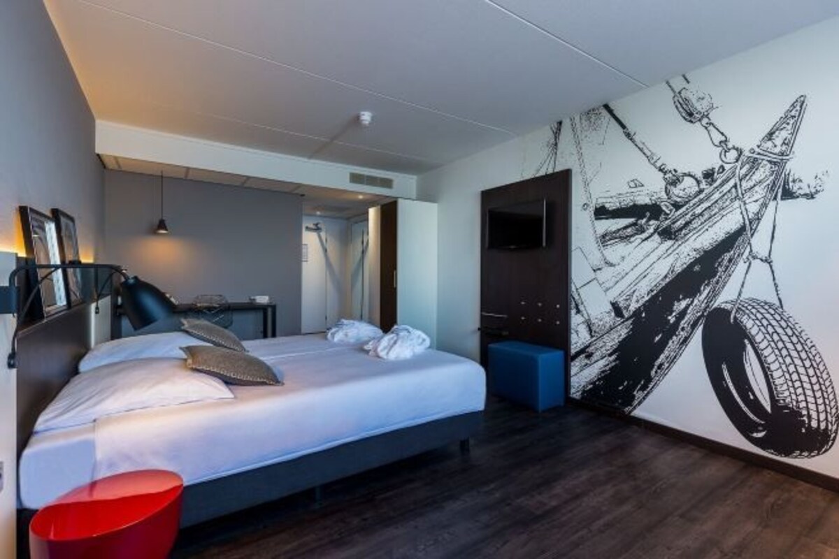 Une chambre d’hôtel moderne, dotée d’un grand lit, d’un bureau et d’une fresque murale.