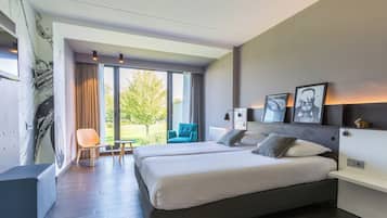 Moderni hotellihuone, jossa on suuri sänky, oleskelualue tuolilla sekä näkymä ulos.