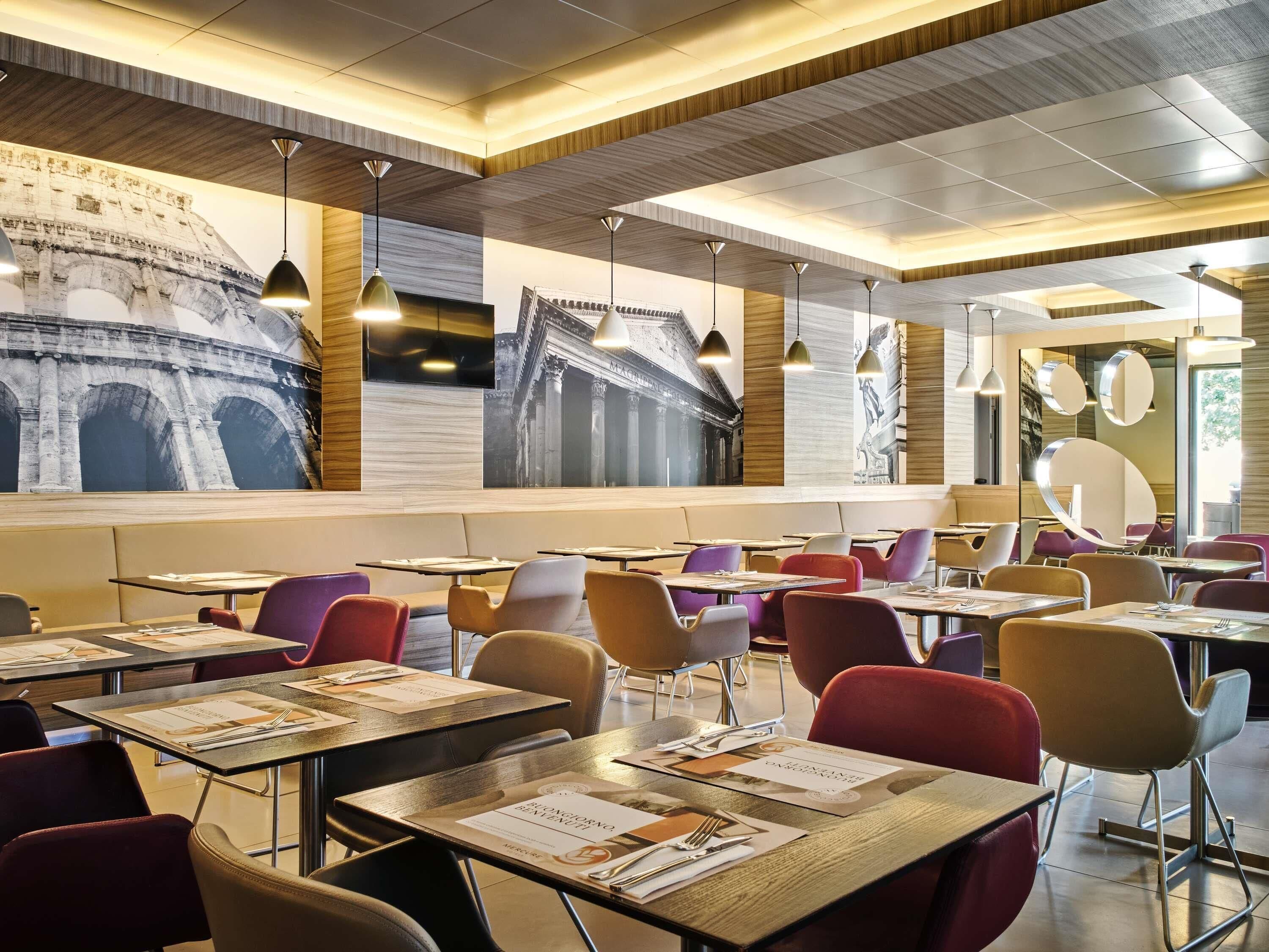 Un interior de restaurante moderno con mesas altas, sillas coloridas y murales grandes en las paredes.