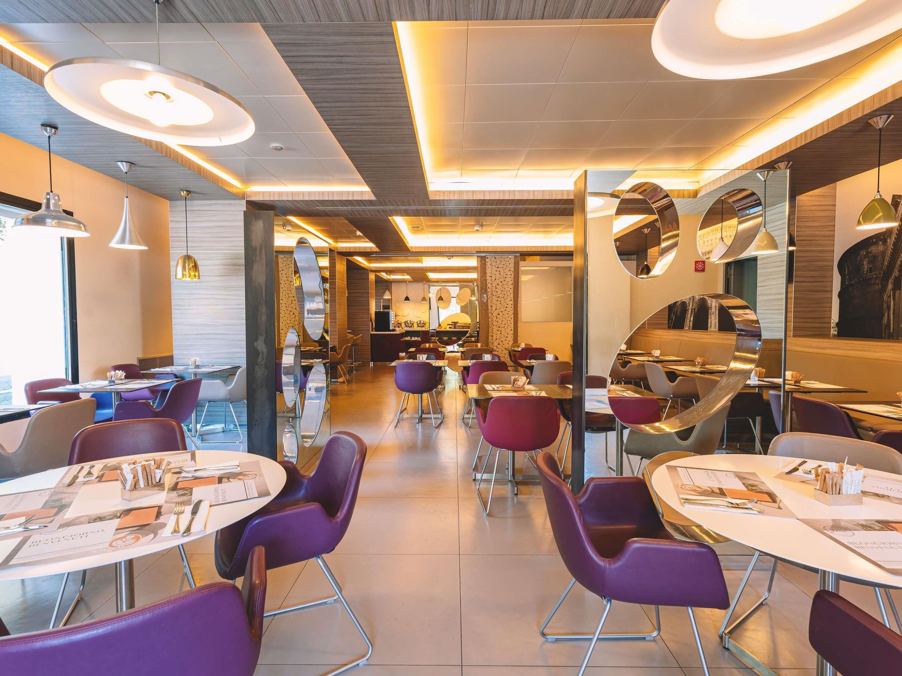 A modern restaurant interior with round tables, purple chairs, and pendant lighting.