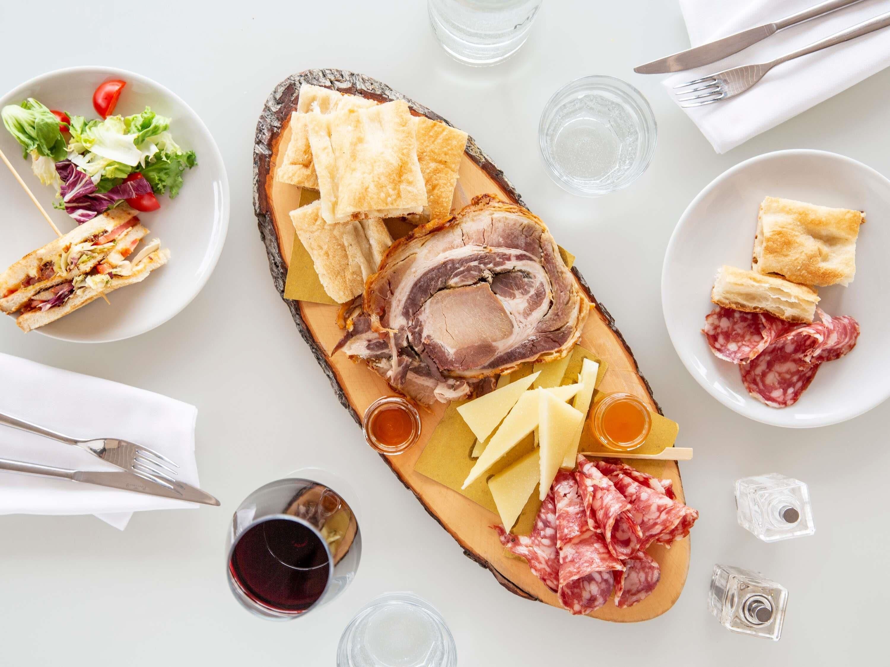 A meal with bread, meat, cheese, and a salad on a wooden board.