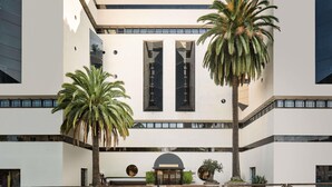 Un edificio moderno con un atrio central, ventanas amplias y palmeras.