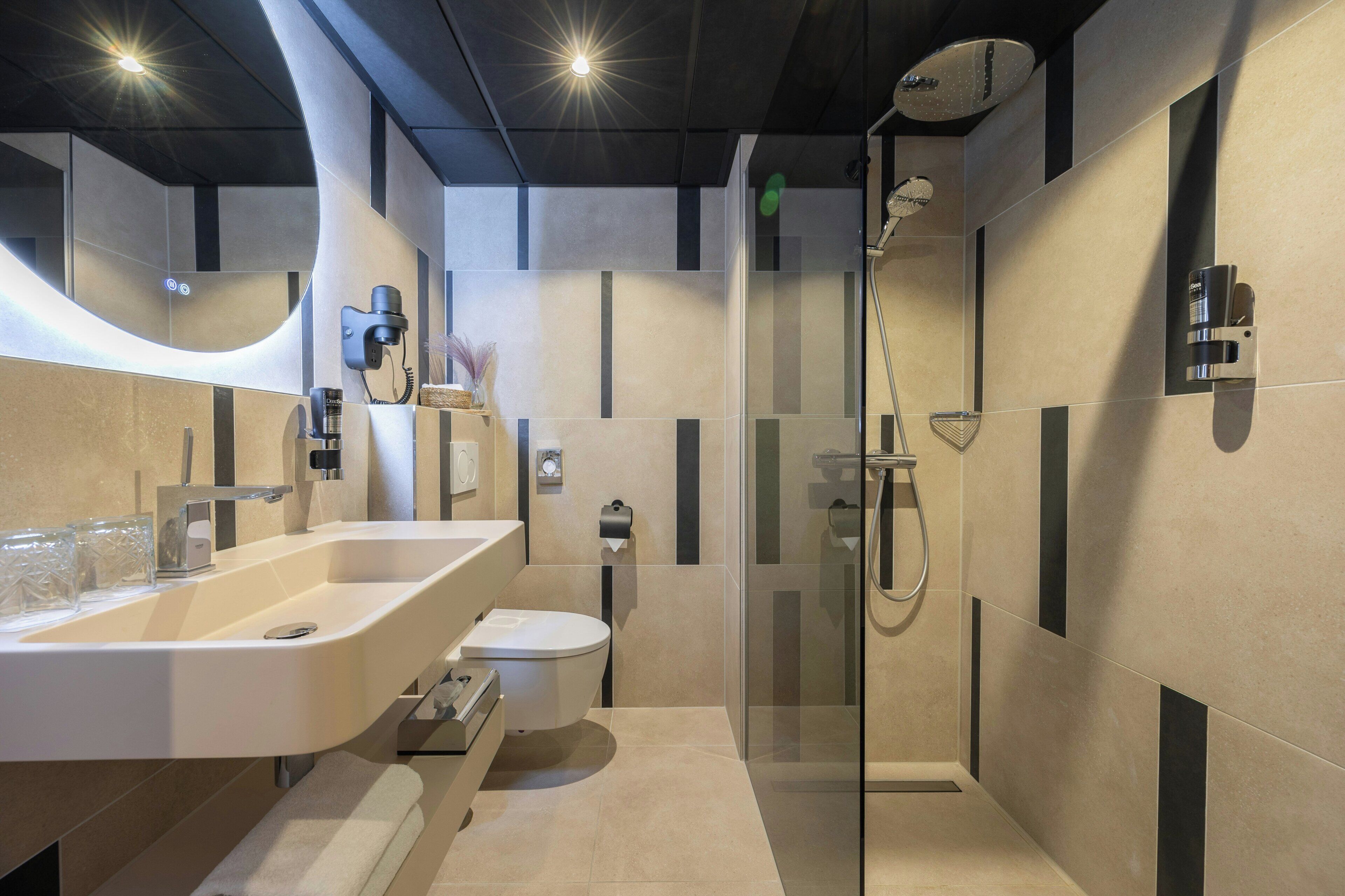 Een moderne badkamer met een douchecabine van glas, een wastafelmeubel met dubbele wastafel en een toilet.