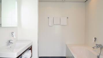 Un baño moderno con un lavamanos blanco, una bañera y una zona de ducha.