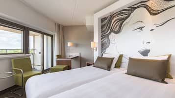 Una habitación de hotel con una cama grande, un escritorio, una silla y una ventana con cortinas.