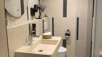 A modern bathroom with a large mirror, a sink, a toilet, and a shower area.