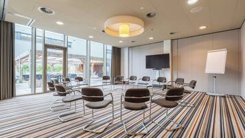 A conference room with a striped carpet, chairs arranged in a semi-circle, a large screen, and a whiteboard.