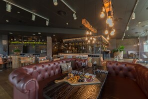 Un restaurante moderno con asientos de cuero, una mesa de madera con comida y una zona de bar al fondo.