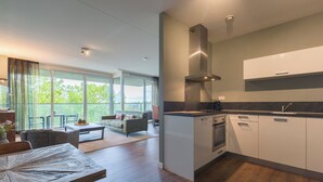 Una cocina moderna con armarios blancos, una campana extractora de acero inoxidable y un amplio ventanal con vistas a un balcón.